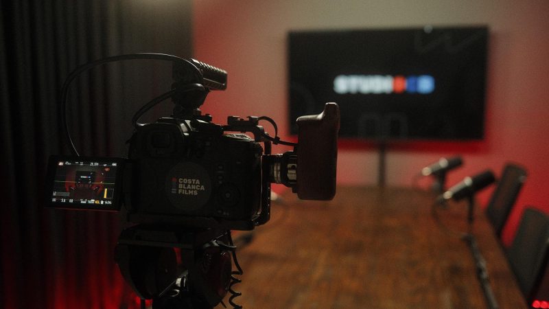 Visor da câmera filmadora mostrando o cenário do estúdio com fundo vermelho. Monitoramento de imagem em tempo real.