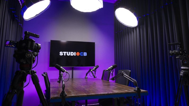 Estúdio de podcast completo no Rio de Janeiro com iluminação LED RGB e microfones profissionais na mesa.